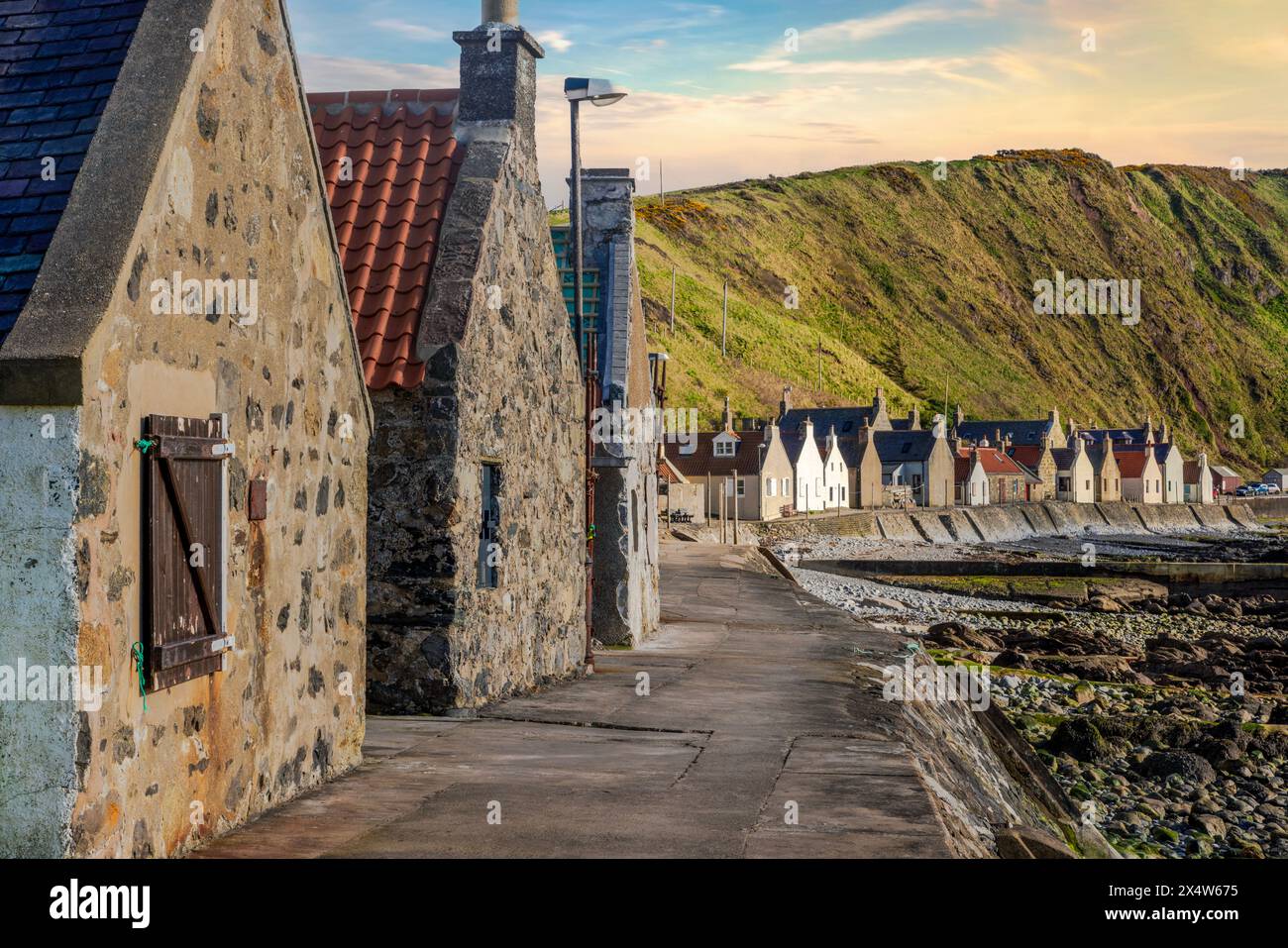 Crovie, ein winziges Fischerdorf in Aberdeenshire, schmiegt sich an einen schmalen Felsvorsprung zwischen dem Meer und den hohen Klippen und schafft so eine einzigartige malerische Szene. Stockfoto