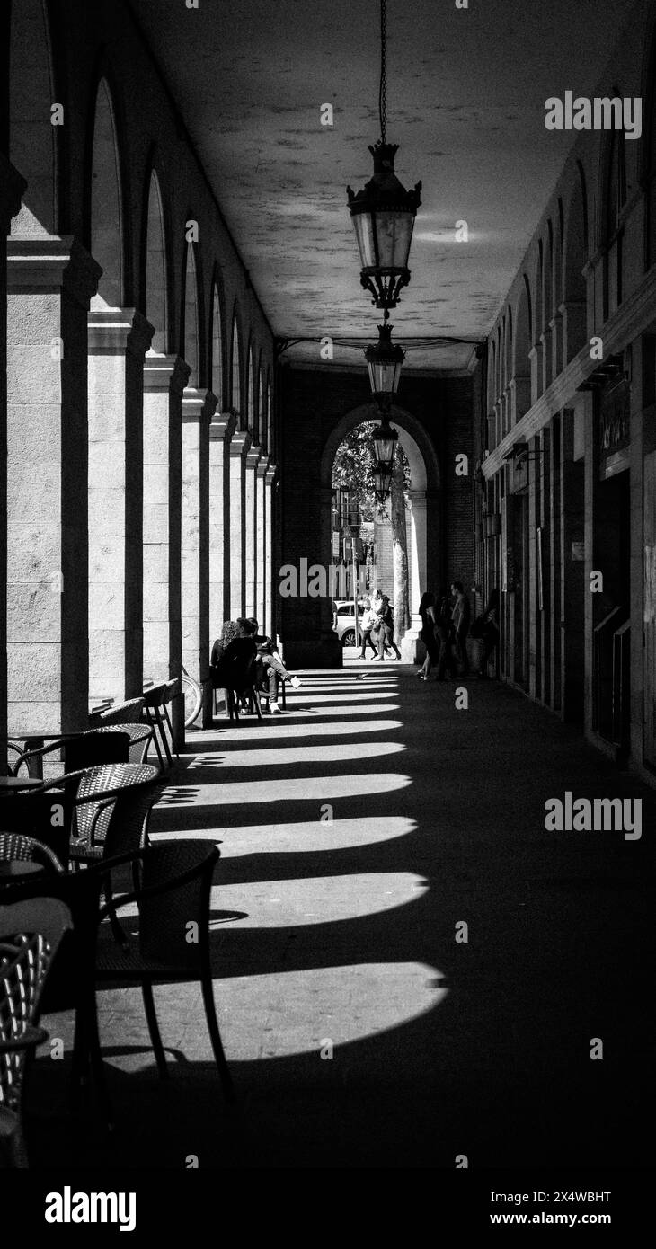 Sonnenlicht durch die Bögen einer Kolonnade wirft perfekte Schatten auf den Steinboden Stockfoto