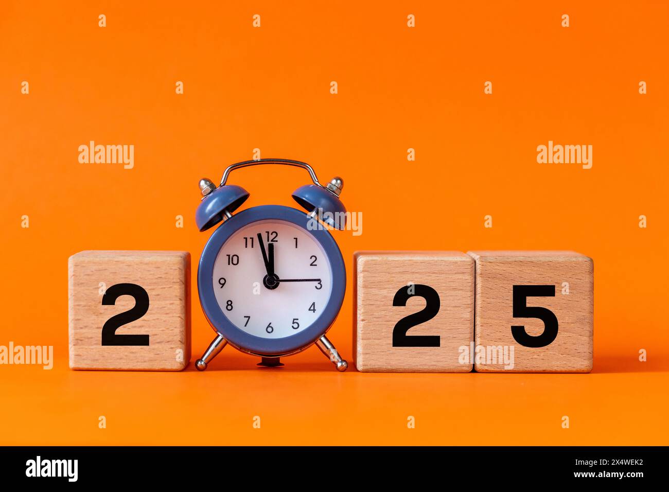 2025, Geschäftskonzept, Symbol für das neue Jahr. Der graue Wecker zählt bis 12. Schöner oranger Hintergrund, Kopierraum. 2025 Happy New Year Stockfoto
