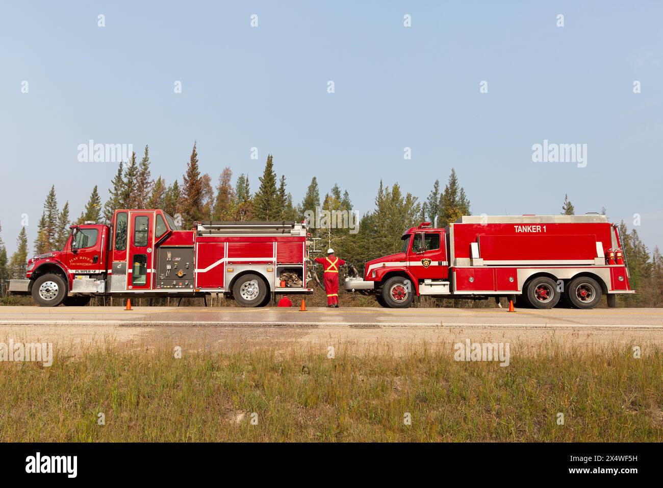 Hay River Feuerwehrfahrzeuge entlang der Autobahn während eines Waldbrandes in den Nordwest-Territorien, Kanada. Mehr als 4 Millionen Hektar Wald verbrannten in der Saison 2023. Stockfoto
