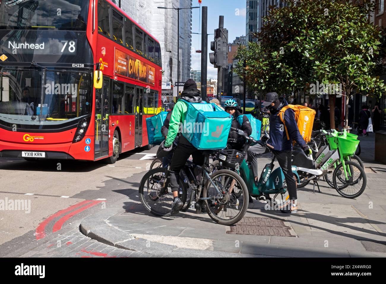 Kuriere Arbeiter Männer Fahrer auf Fahrrädern mit Essenslieferrädern und rotem Doppeldeckerbus auf der Liverpool Street in London England 2024 KATHY DEWITT Stockfoto