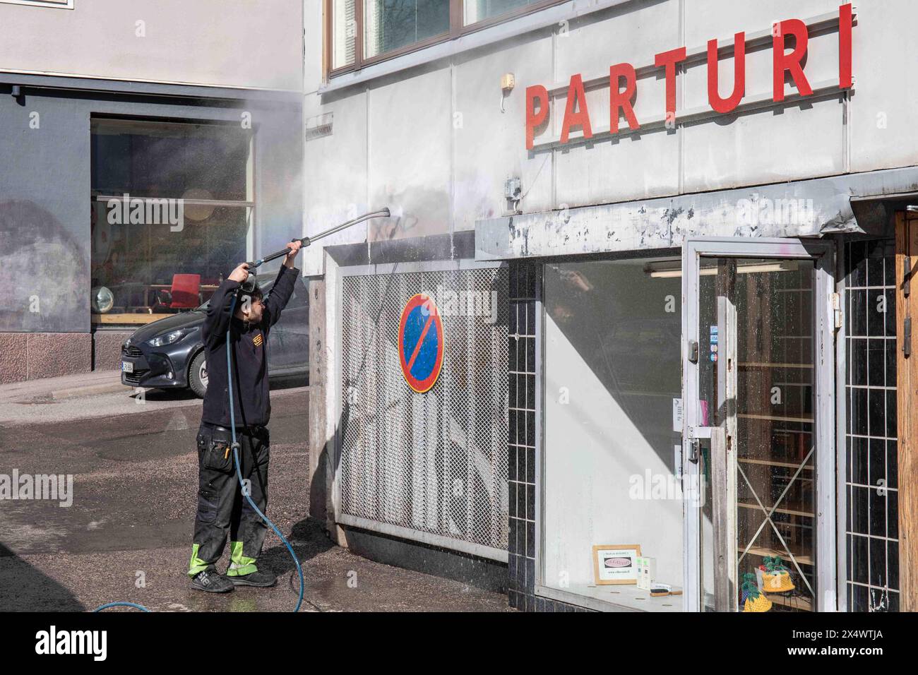 Der Wartungspersonal entfernt Graffiti von der Wand mit einem Hochdruckreiniger in Fleminginkatu 19 im Bezirk Harju in Helsinki, Finnland Stockfoto
