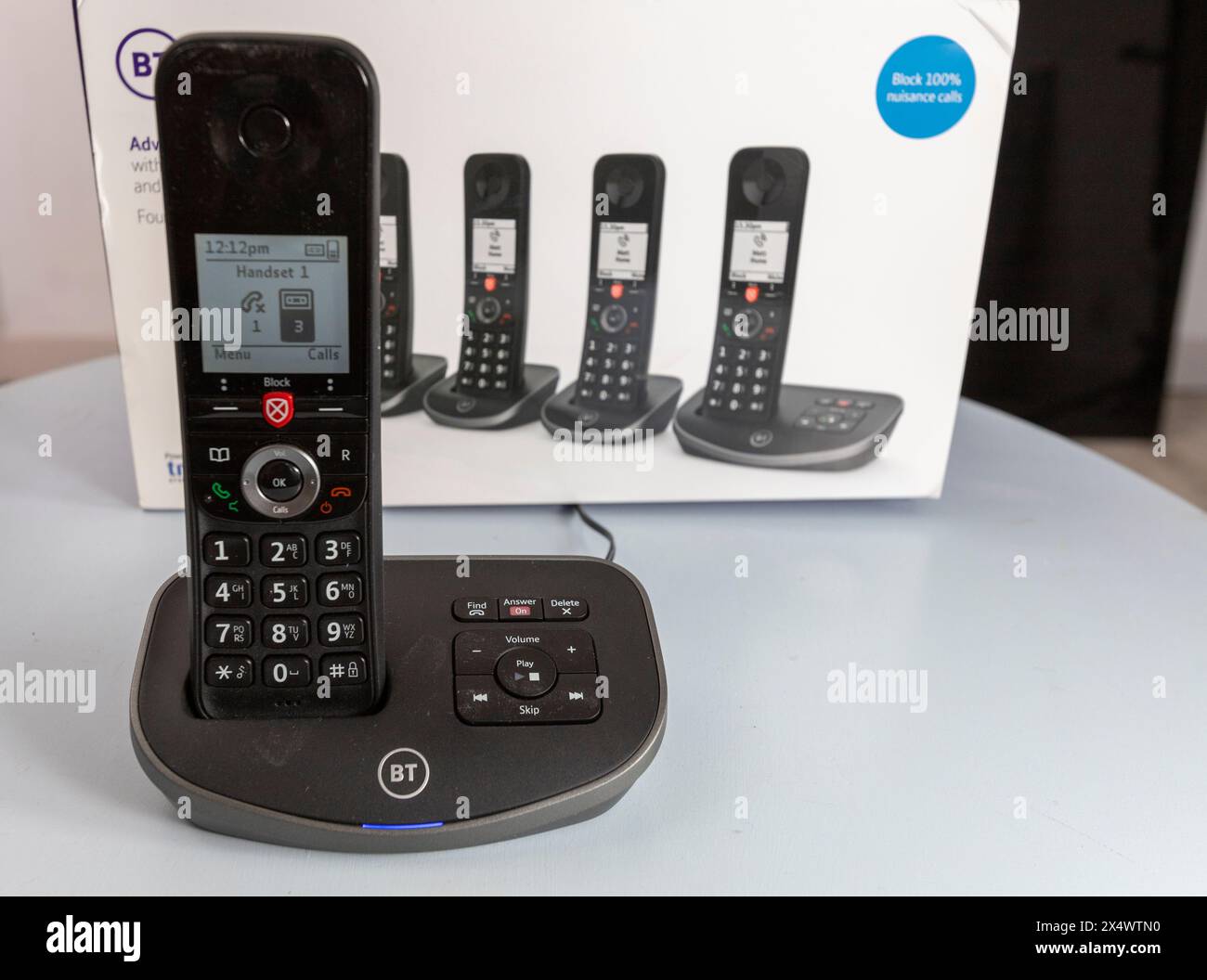 BT schnurlose analoge Telefone mit Basisstation, Anrufsperre, Anrufbeantworter, die Pappschachtel, die sie auf einem hellblauen Tisch fanden Stockfoto