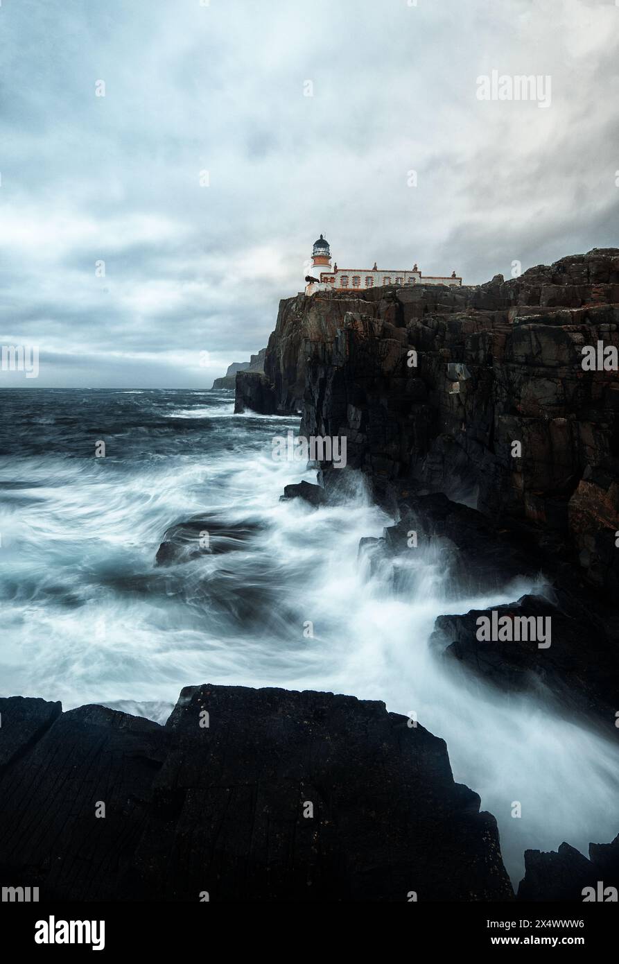 Neist Point Lighthouse – wilde Wellen krachen gegen die zerklüfteten Klippen und senden Schaum in die Luft, als ob man versuchen würde, den Leuchtturm zu erreichen. Stockfoto