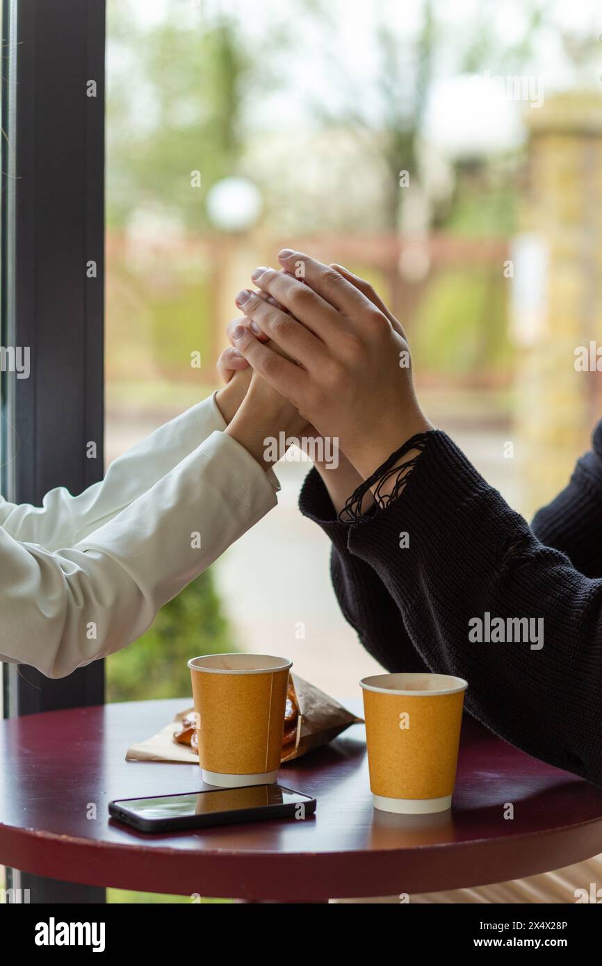 Ein Paar genießt einen Kaffee und hält Hände. Hände halten, die Hände eines Paares, das sich liebt. Bokeh-Porträtfoto-Konzept. Stockfoto