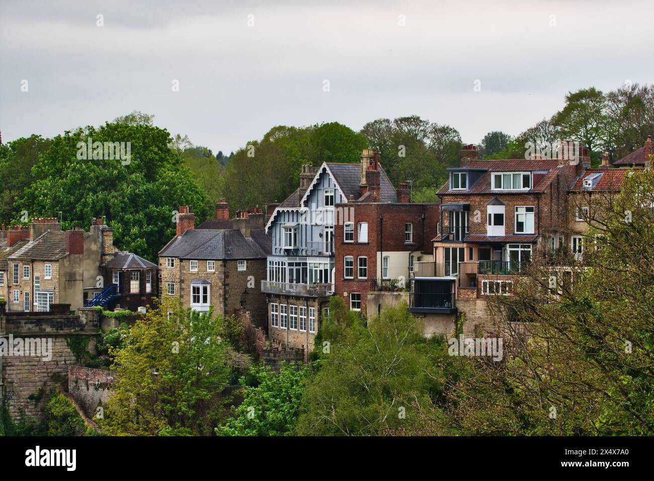 Malerischer Blick auf traditionelle britische Häuser auf einem Hügel, umgeben von üppigem Grün im Frühling. Stockfoto