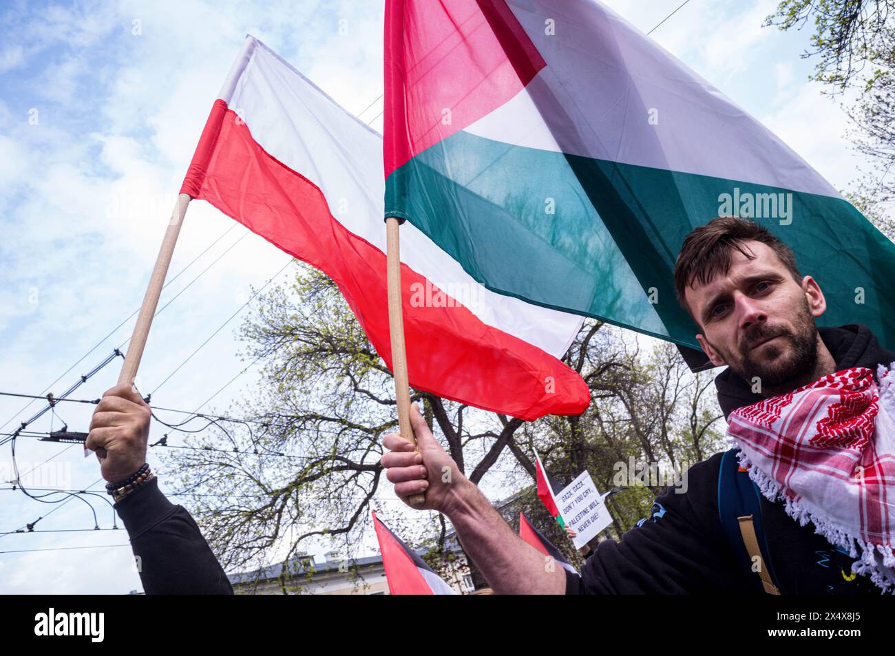 14. April 2024, Warschau, Mazowieckie, Polen: Teilnehmer hissen während der Kundgebung die palästinensische Flagge neben der polnischen Flagge. Als April begann, wurde die Zahl der Todesopfer von 32.000 in Gaza überschritten, von denen 13.000 Kinder waren. Pro-palästinensische Anhänger in Warschau versammelten sich, um Solidarität mit dem Volk von Gaza zu zeigen und gegen den anhaltenden Völkermord Israels zu protestieren. Die Demonstranten versammelten sich am Plac Zbawiciela und gingen zur israelischen Botschaft. 50m von der Botschaft entfernt hindert die Polizei die Demonstranten daran, weiter zu gehen, was zu Spannungen führt. Durch die Verhandlungen war der marsch vollzogen Stockfoto