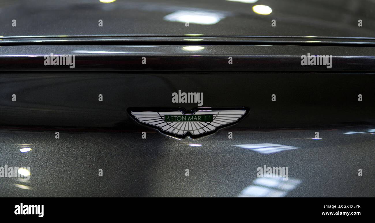 Detail eines Emblems von Aston Martin auf der Motorhaube eines grauen Autos Stockfoto