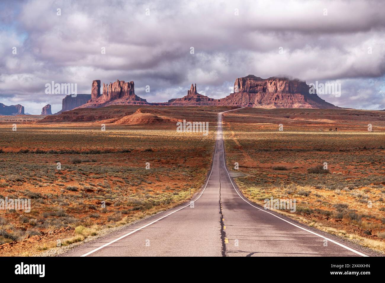 Blick auf die Forrest Gump Scenic Road im Monument Valley, Utah, während eines bewölkten Tages, zeigt die lange, einsame Straße, die durch den berühmten Berg nach Arizona führt Stockfoto Blick auf die Forrest Gump Scenic Road im Monument Valley, Utah, während eines bewölkten Tages, zeigt die lange, einsame Straße, die durch den berühmten Berg nach Arizona führt Stockfoto