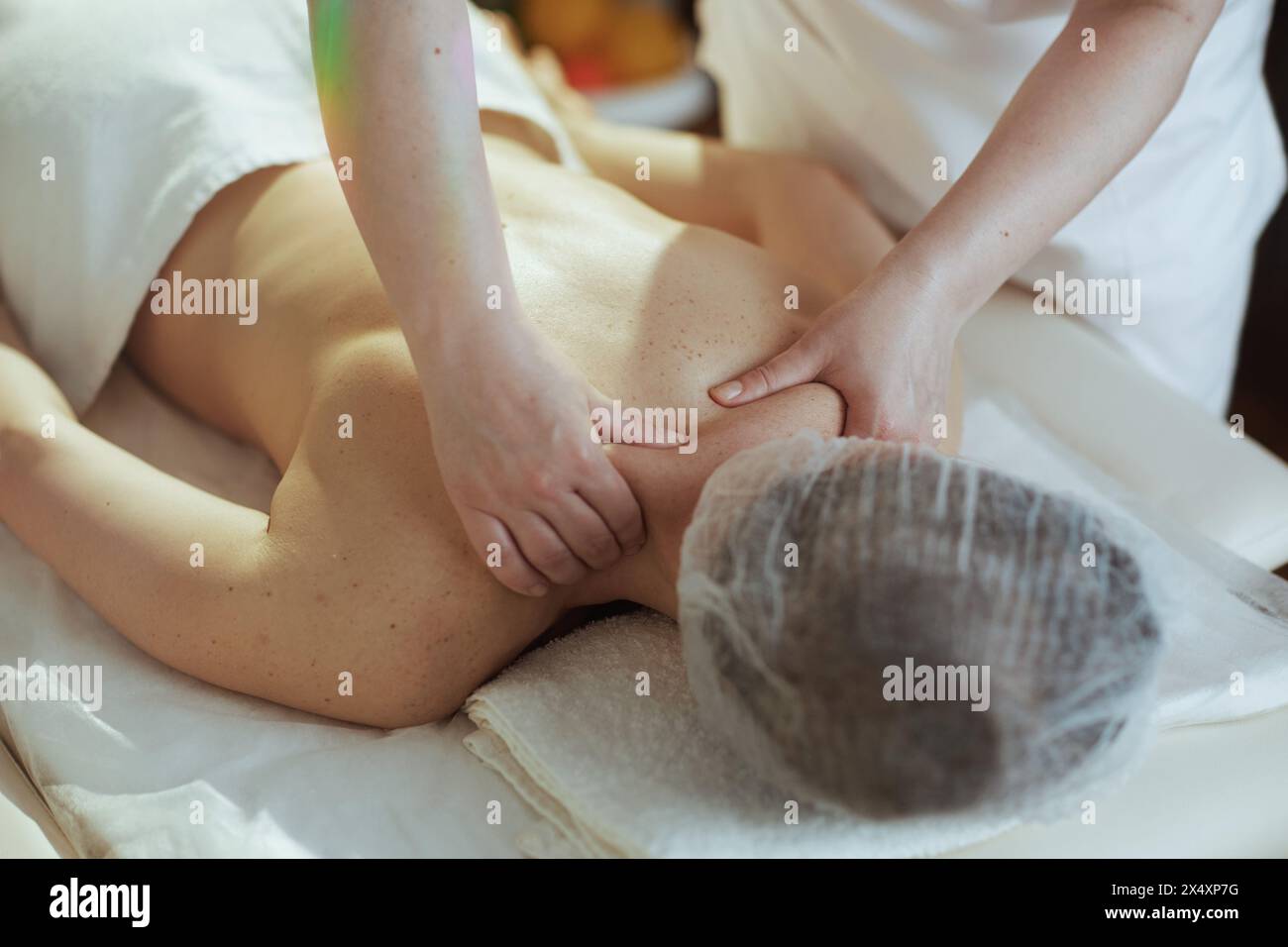 Gesundheitszeit. Medizinischer Massagetherapeut im Spa-Salon, der Klienten den Hals auf dem Massagetisch massiert. Stockfoto