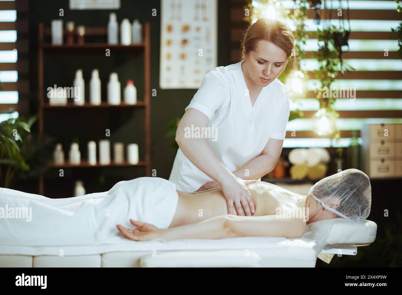 Gesundheitszeit. Medizinischer Massagetherapeut im Spa-Salon Massagekunde auf Massagetisch. Stockfoto