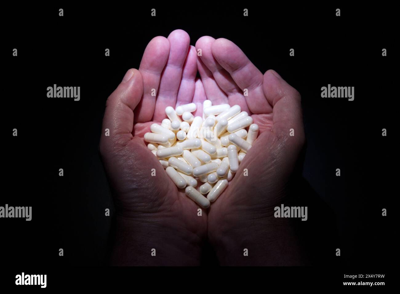 Ein Paar Hände, die Tabletten in Form eines Herzens halten Stockfoto