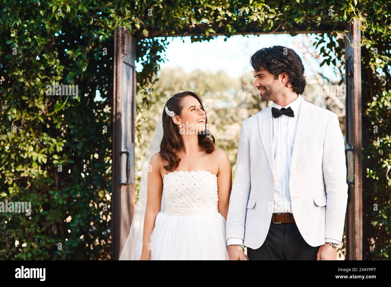 Glückliches Paar, Hochzeit und Händchenhalten mit Liebe durch Eintritt zur Ehe, Unterstützung oder Vertrauen in die Natur. Mann und Frau oder Braut und Bräutigam mit einem Lächeln Stockfoto