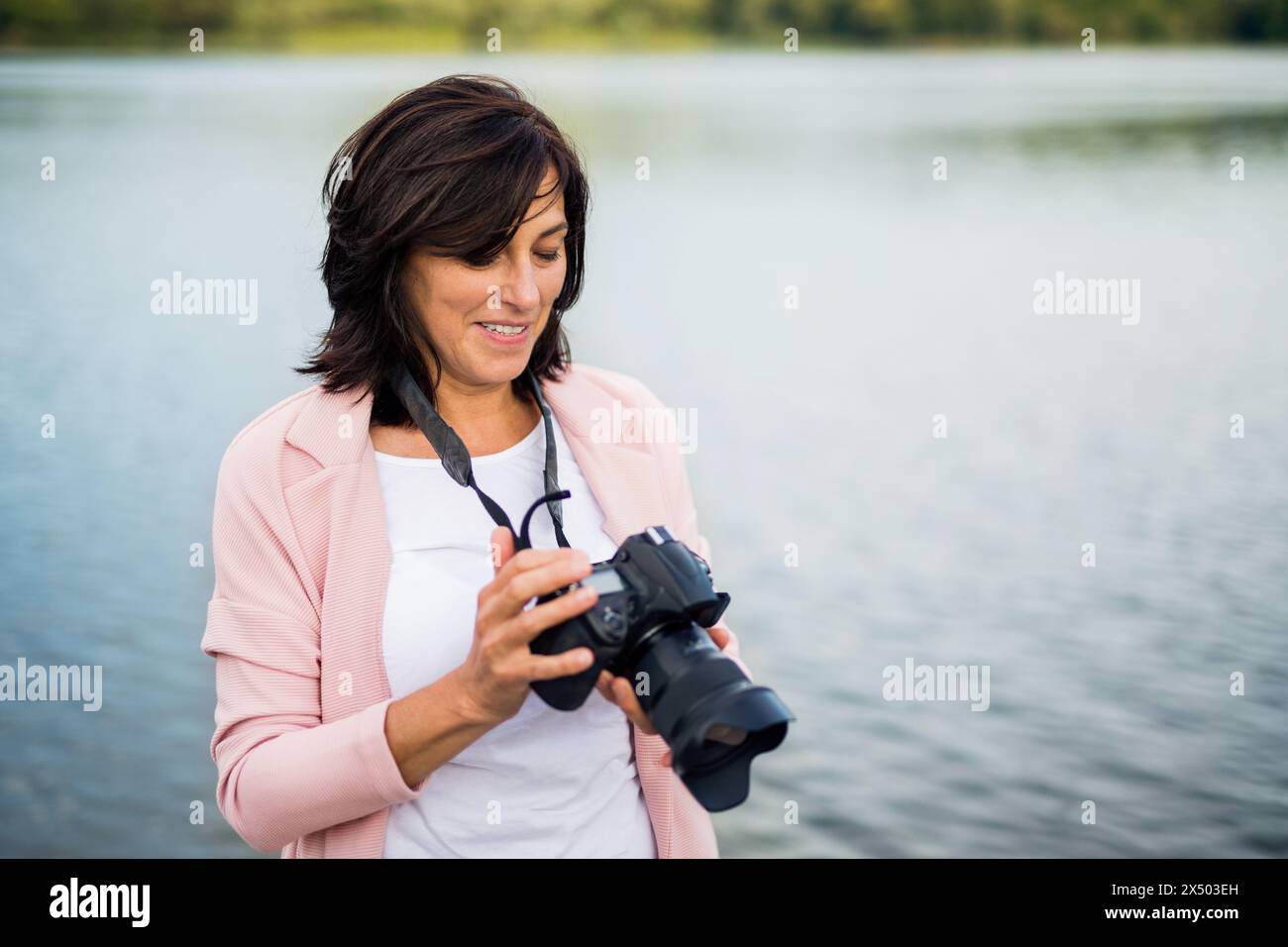 Porträt einer schönen reiferen Frau im Urlaub, die Fotos mit einer professionellen Kamera macht und die Schönheit der Natur um sie herum festnimmt. Stockfoto