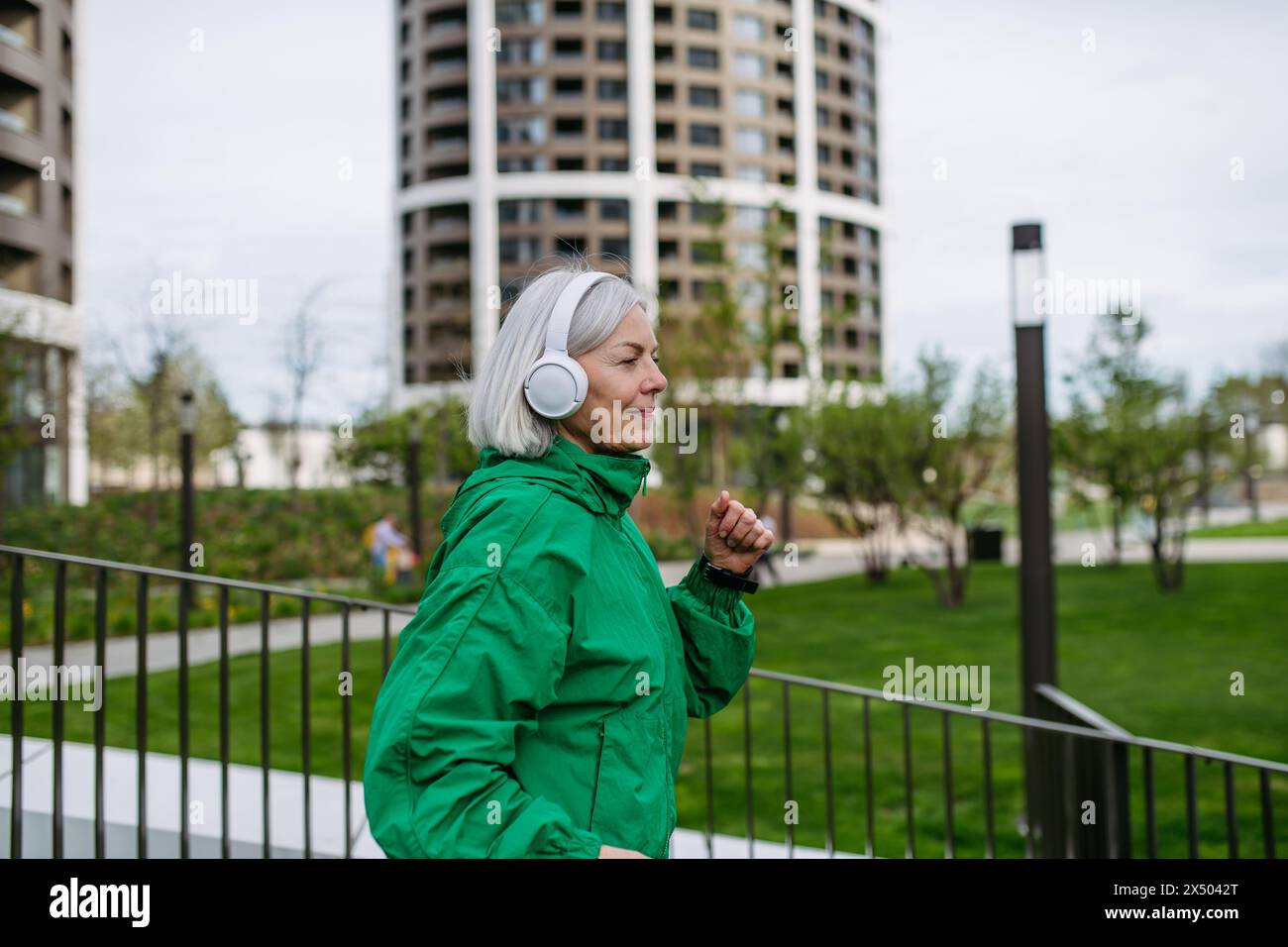 Reife Frau, die Musik hört, während sie läuft. Sport nach der Arbeit für gute psychische Gesundheit, körperliche Gesundheit, Stressabbau und Stimmung. Stockfoto