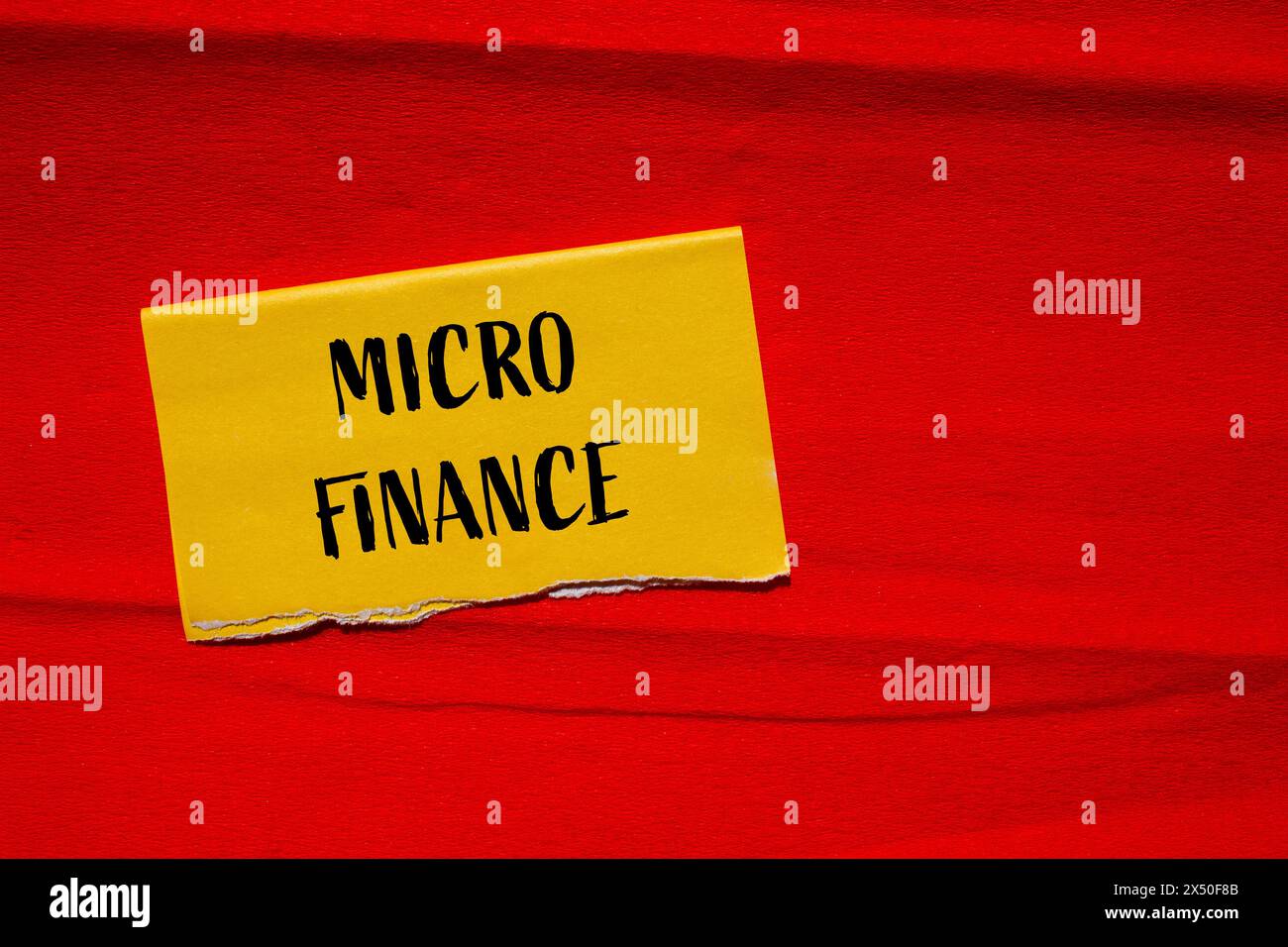 Wörter aus dem Mikrofinanzbereich auf gelbem Papier mit rotem Hintergrund. Konzeptionelles Geschäftssymbol für Mikrofinanzen. Kopierbereich. Stockfoto