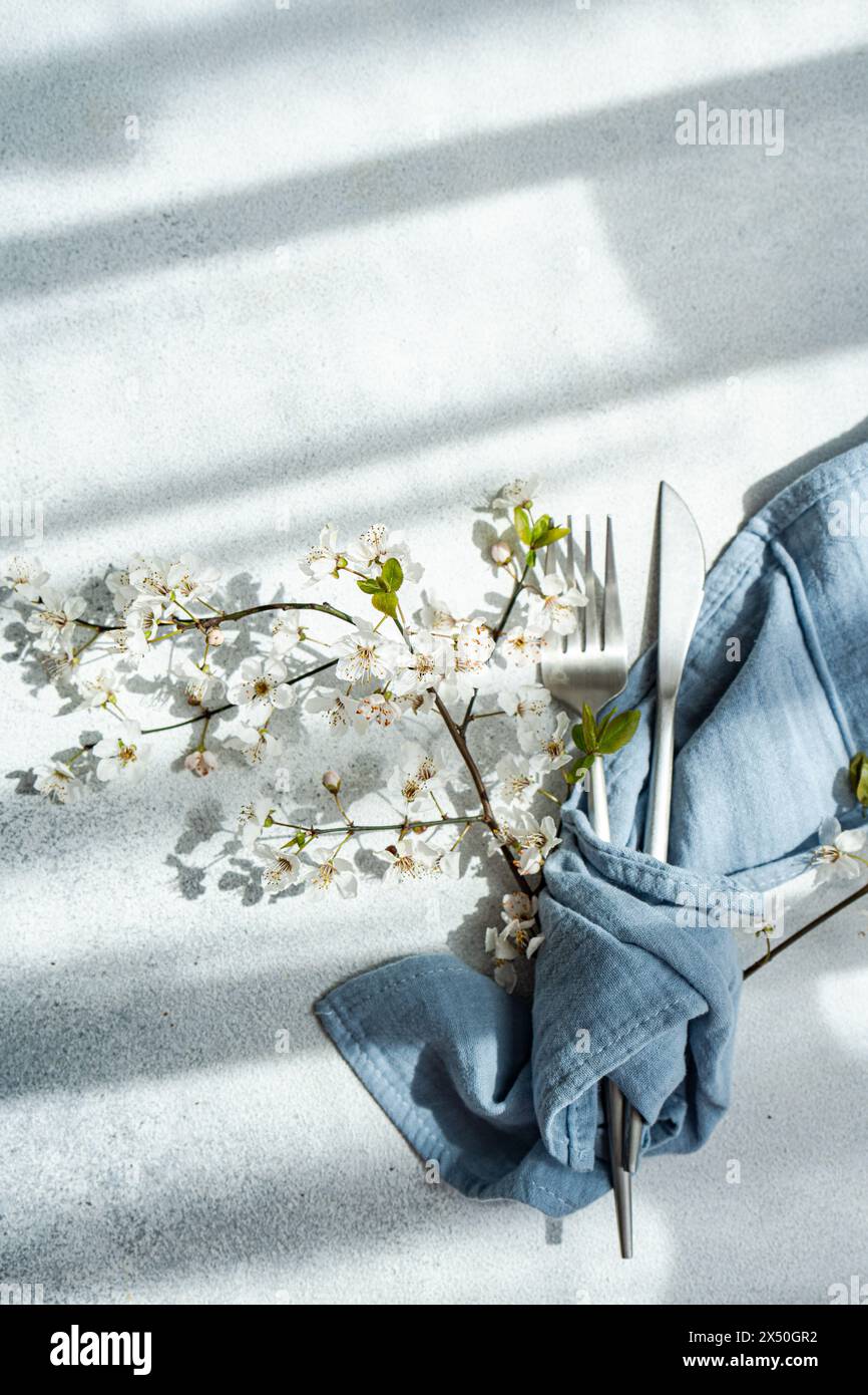 Draufsicht auf ein Besteck mit Serviette und Kirschblütenzweigen in voller Blüte auf einem Tisch Stockfoto