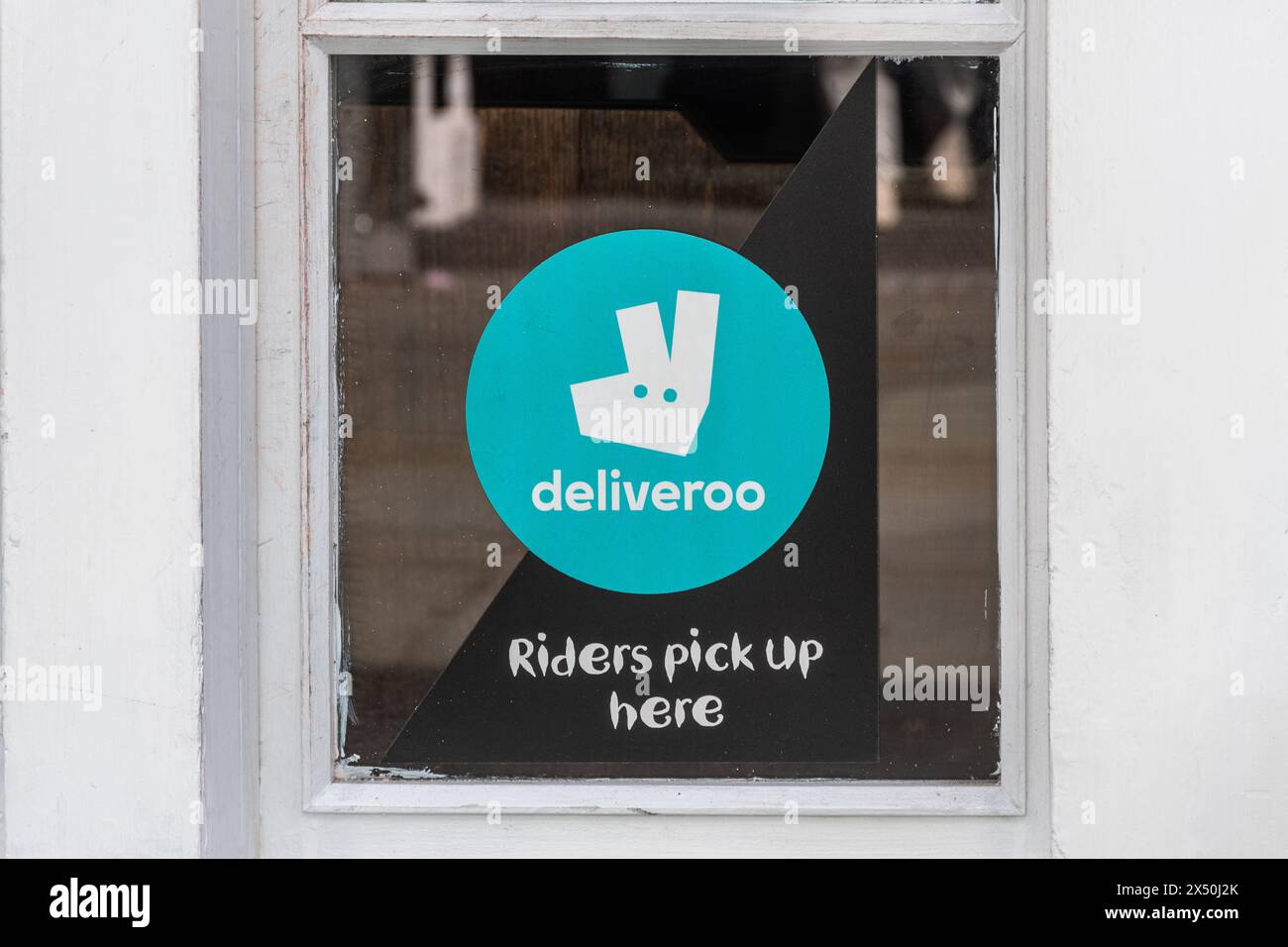 Deliveroo Logo auf dem Imbissgeschäft mit Schild „Riders Pick Up Here“, England, Großbritannien Stockfoto