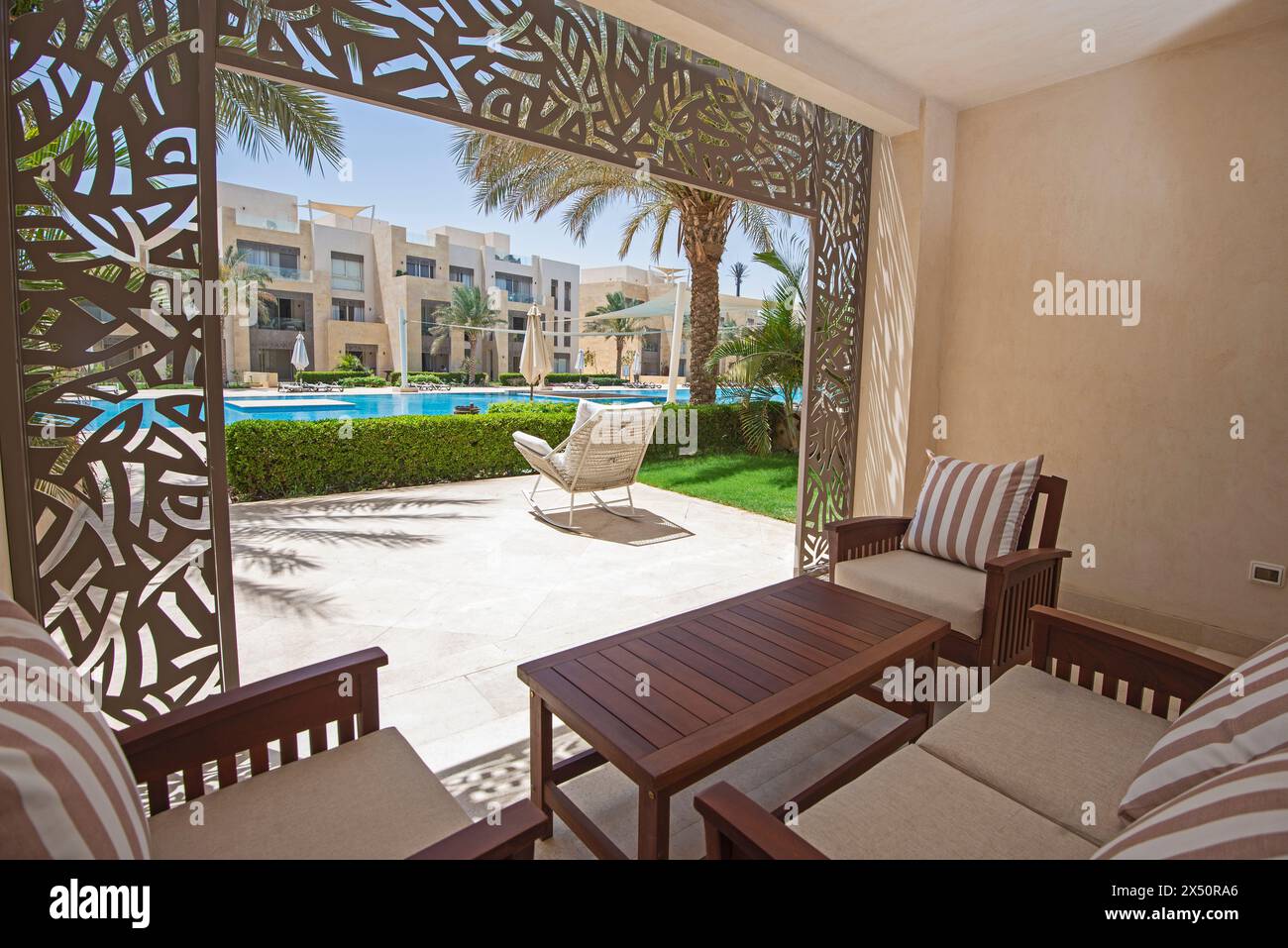 Gartenterrasse eines luxuriösen Apartmenthauses in tropischem Resort mit Möbeln und Blick auf den Swimmingpool Stockfoto