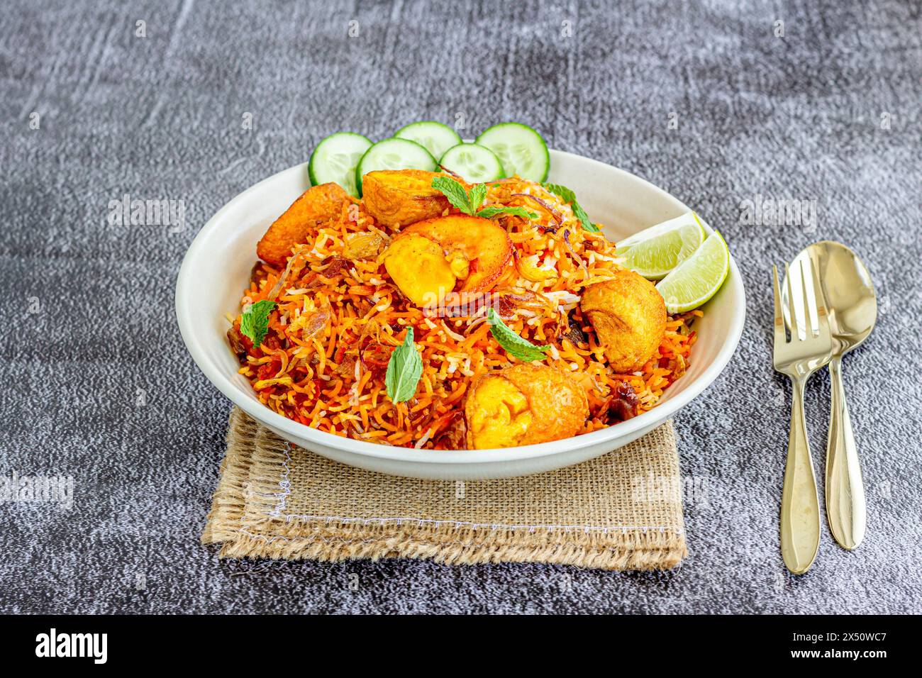 Indisches Gewürz-Ei-Reis-Gericht serviert mit Joghurt, Gurke und Koriander garniert mit frischen Minzblättern, Egg Biryani close Stockfoto