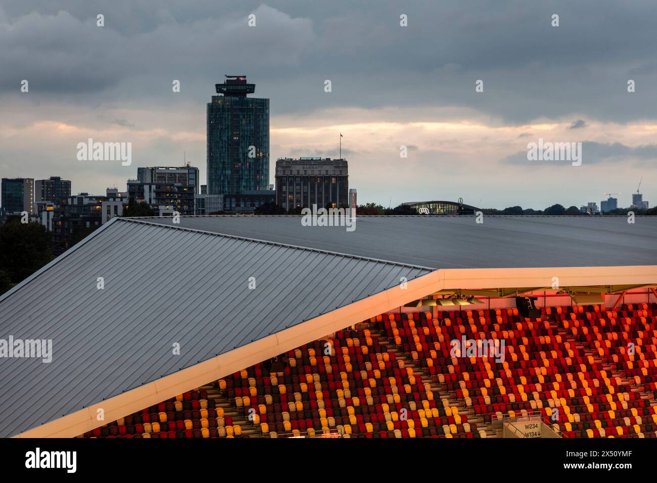 Blick in die Dämmerung über die Stände, die die städtische Lage zeigen. Brentford Community Stadium, Brentford, Vereinigtes Königreich. Architekt: AFL Architects, 2020. Stockfoto