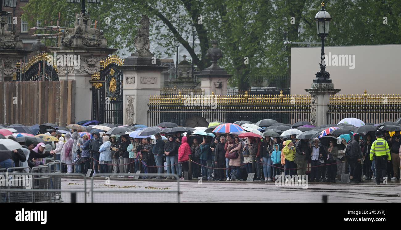 Buckingham Palace, London, Großbritannien. Mai 2024. Große Menschenmassen mit Regenschirmen im Buckingham Palace, während die königliche Truppe Royal Horse Artillery am Mittag einen 41 Gun Royal Salute abfeuert, während die Band of the Irish Guards Musik zum ersten Jahrestag ihrer Majesties The King and Queen's Krönung gab. Quelle: Malcolm Park/Alamy Live News Stockfoto