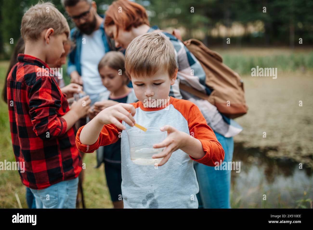 Junge Studenten zur Analyse von Wasserqualität, ph-Wert mit Indikatorstreifen im Biologiefeldunterricht. Lehrerin im Freien Stockfoto