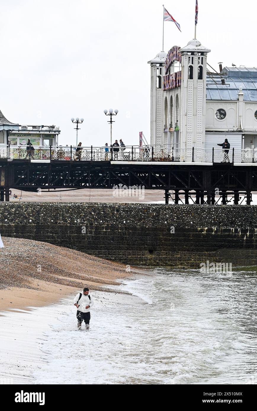 Brighton UK 6. Mai 2024 - dieser Besucher paddelt noch immer am Brighton Palace Pier an einem kalten, feuchten Feiertag Anfang Mai: Credit Simon Dack / Alamy Live News Stockfoto