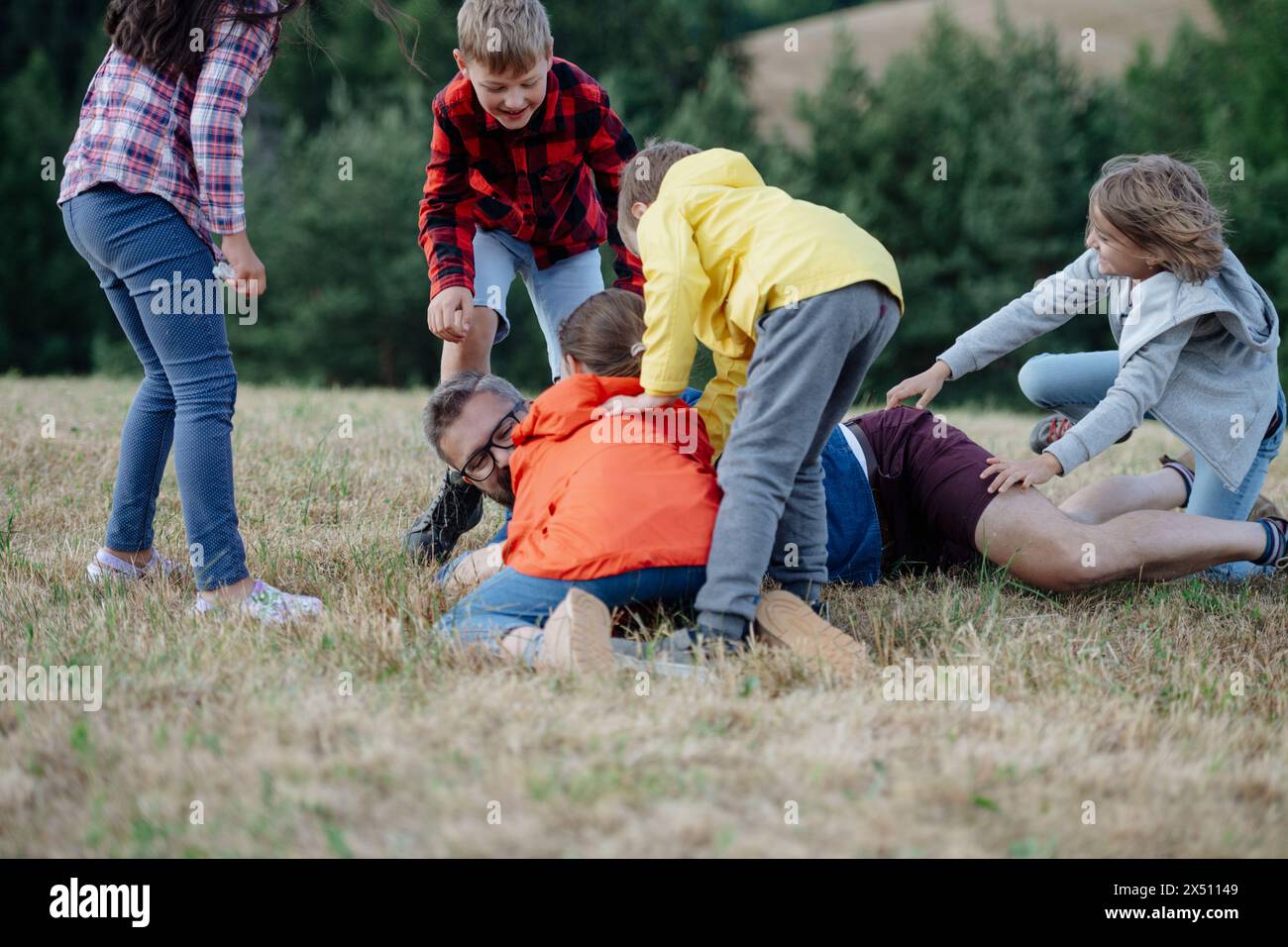 Junge Schüler spielen mit dem Lehrer im Freien, in der Natur, während des Feldunterrichts, laufen mit Ball. Engagierte Lehrer während der Aktivitäten im Freien Stockfoto