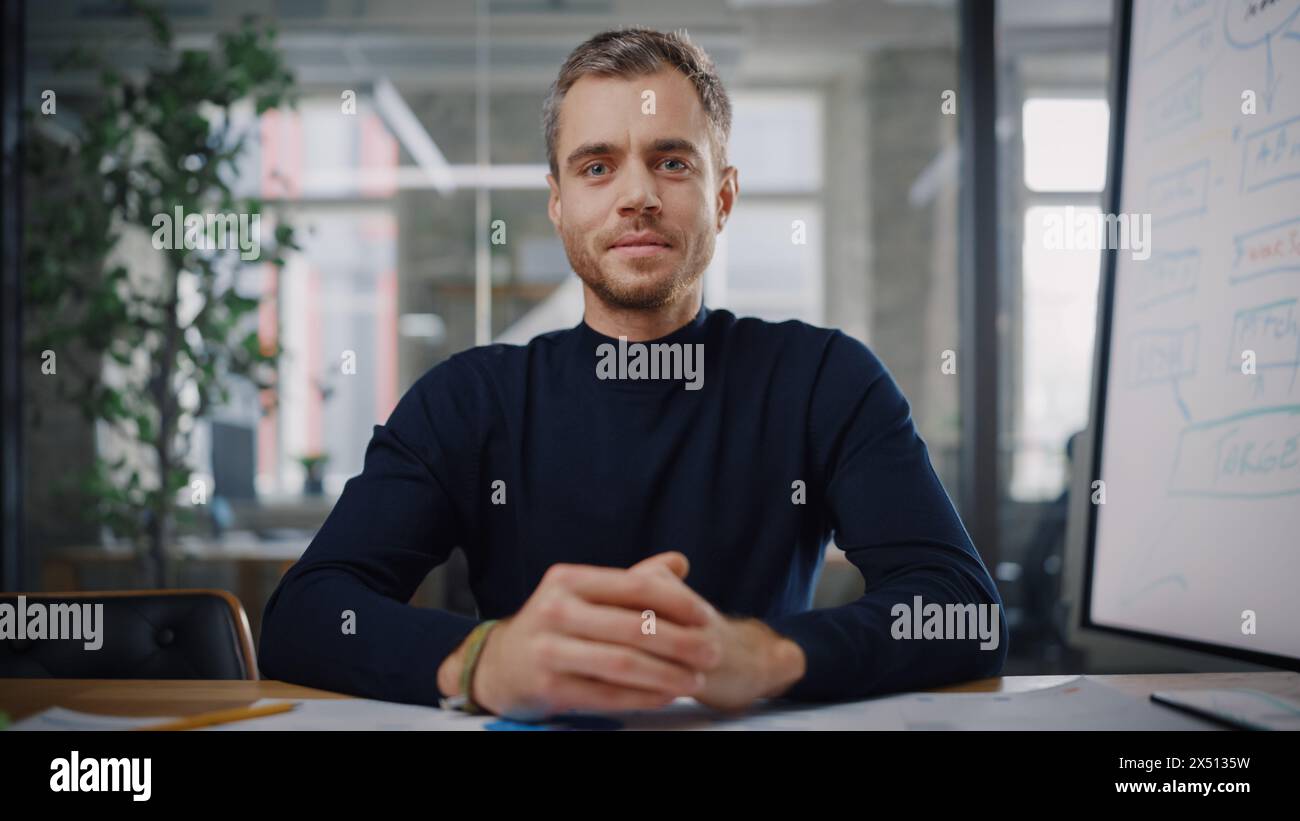 Blickwinkel von der Kamera aus, während ein junger Projektmanager in einer kreativen Büroumgebung einen Videoanruf führt. Glücklicher kaukasischer männlicher Spezialist, der mit einem Kollegen über eine Live-Kamera spricht. Stockfoto