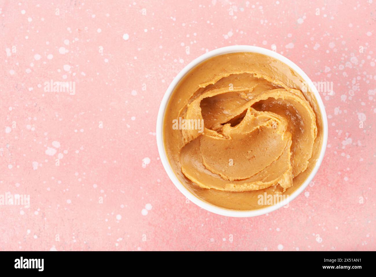 Glatte Erdnussbutter in Schüssel auf rosa Hintergrund Stockfoto