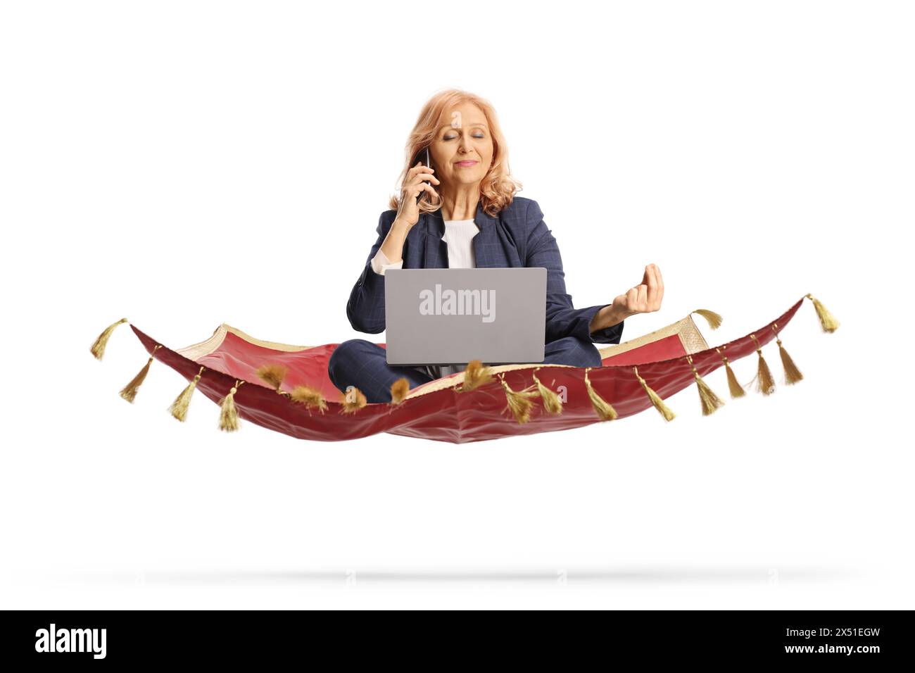 Geschäftsfrau, die einen Laptop und ein Smartphone benutzt und in einer Meditationspose auf einem fliegenden Teppich sitzt, isoliert auf weißem Hintergrund Stockfoto