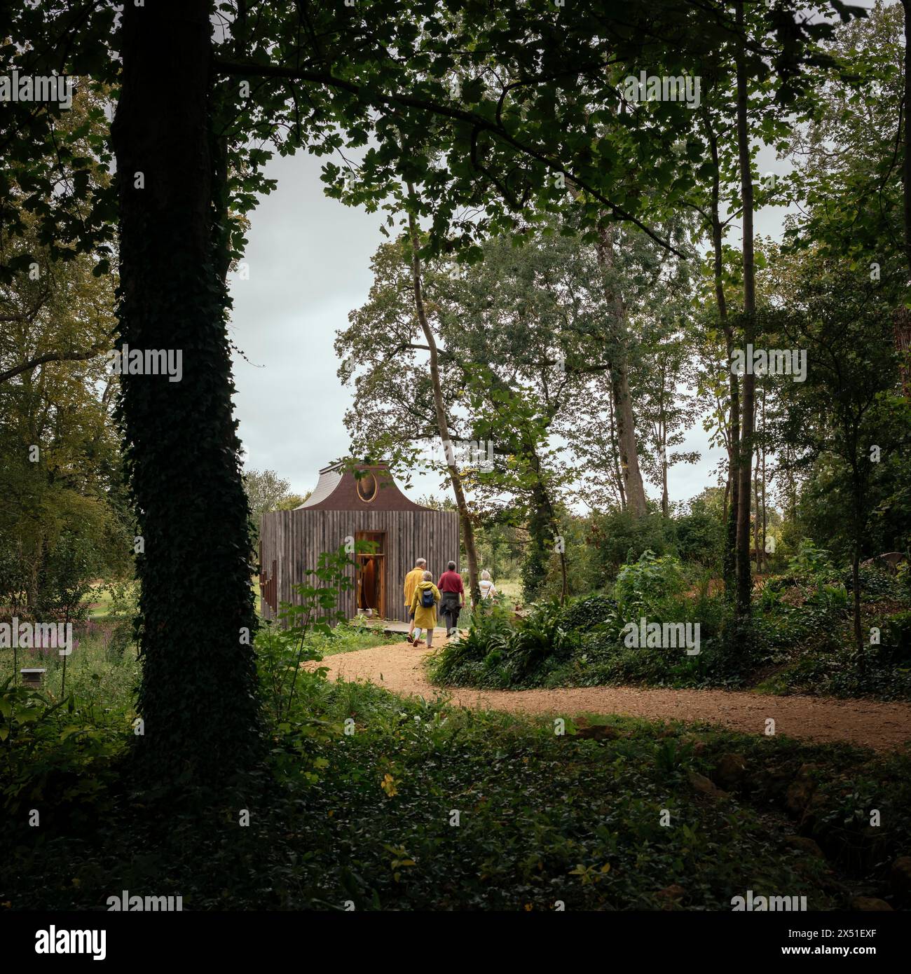 Der Bienenpavillon zwischen den Bäumen mit einem Pfad, der sich ihm zuwindet. Das Beezantium am Newt, Bruton, Vereinigtes Königreich. Architekt: Unsichtbare St Stockfoto