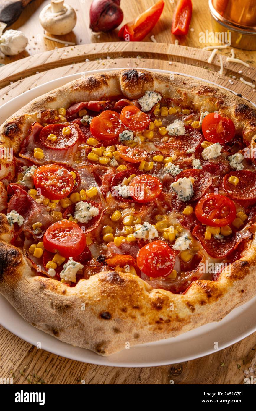 Köstliche italienische Pizza mit Schinken, Tomaten, Blauschimmelkäse und Mais, Nahaufnahme Stockfoto