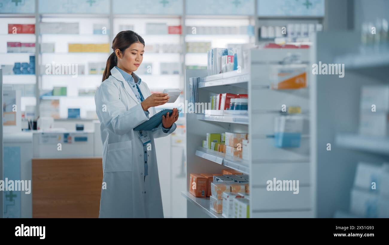 Apotheke Drugstore: Schöne asiatische Apothekerin verwendet Digital Tablet Computer, überprüft Inventar von Medizin, Drogen, Vitamine, Gesundheitsprodukte auf einem Regal. Professioneller Apotheker im Pharmageschäft Stockfoto