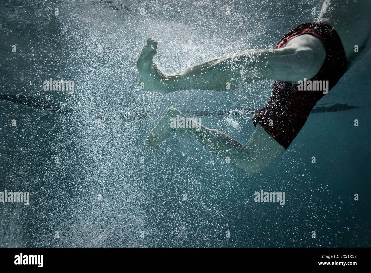 Ein Mann tritt mit den Füßen, während er durch ein Becken schwimmt. Stockfoto