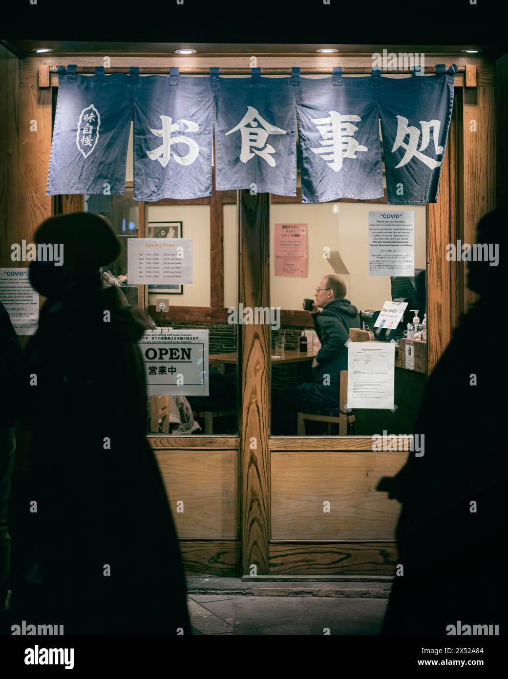 London - 21. November 2021 - Blick auf das Fenster des japanischen Restaurants bei Nacht im warmen Licht, London, Großbritannien Stockfoto