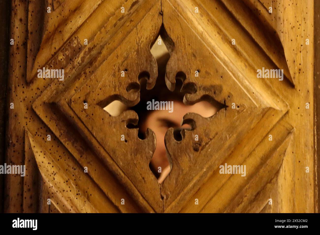 Ein Mensch taucht in die Vergangenheit ein und durchsucht sorgfältig die komplizierten Details einer Vintage-Holztür und enthüllt die Geheimnisse vergangener Zeiten. Stockfoto