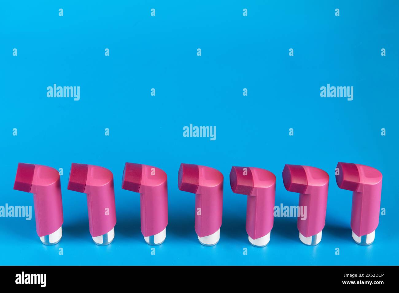 Asthma-Inhalatoren hintereinander auf blauem Hintergrund mit Kopierraum Stockfoto
