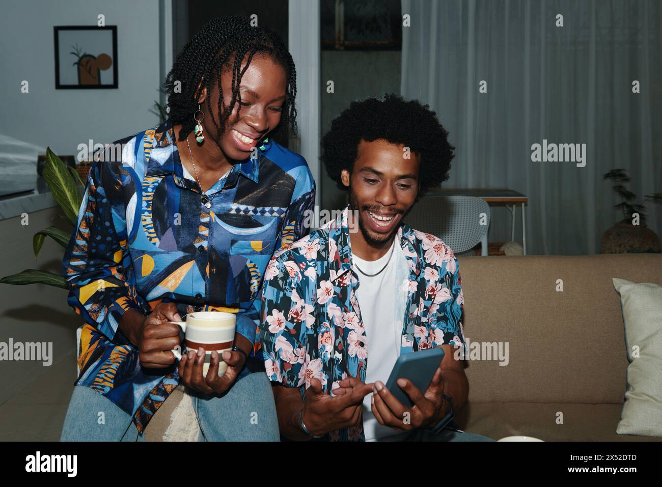 Ein lächelnder Schwarzer Mann und eine Frau diskutieren Beiträge in sozialen Medien Stockfoto