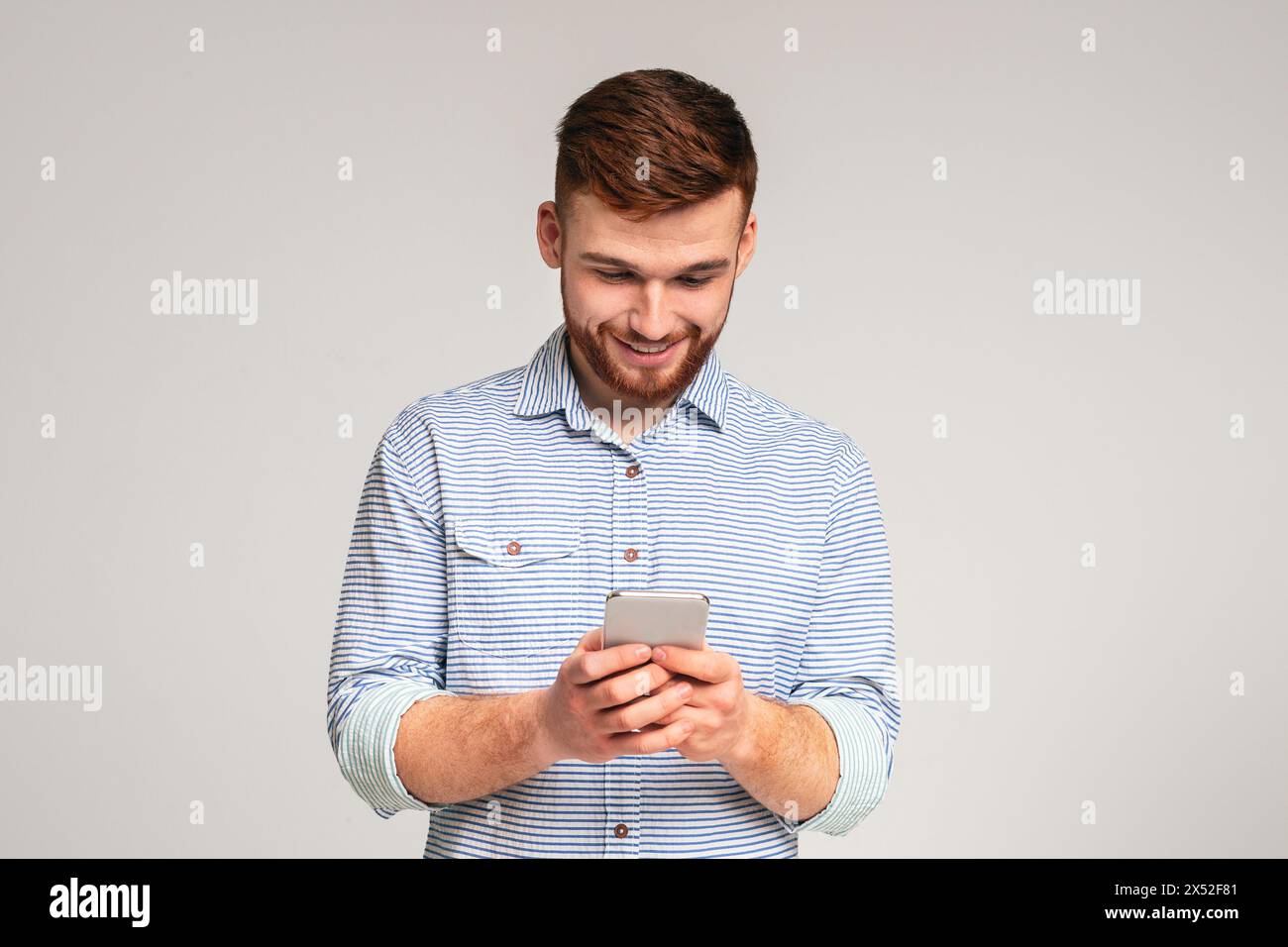 Junger Mann absorbedly Sms auf seinem Handy Stockfoto