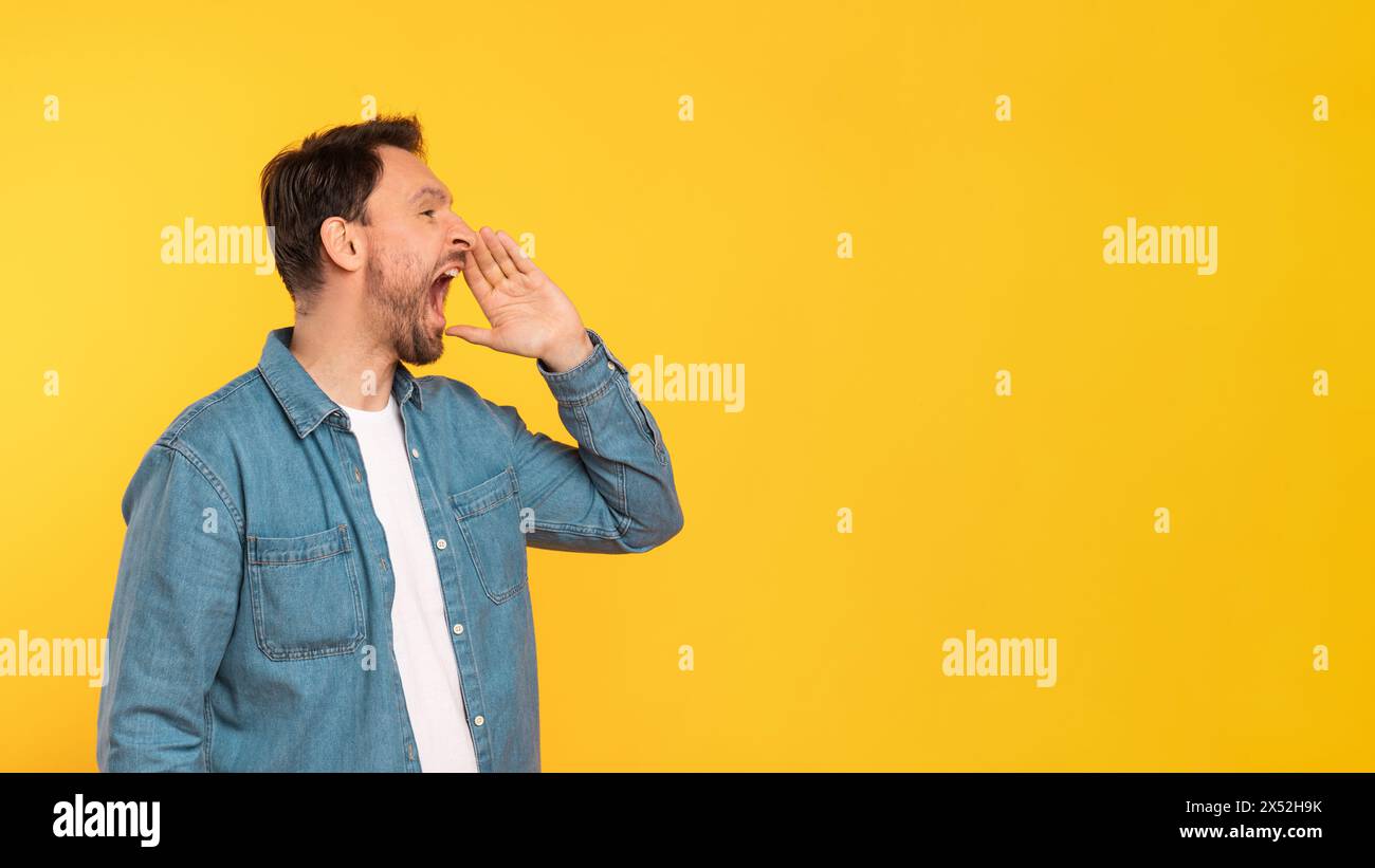 Mann steht vor der gelben Mauer und schreiend Stockfoto