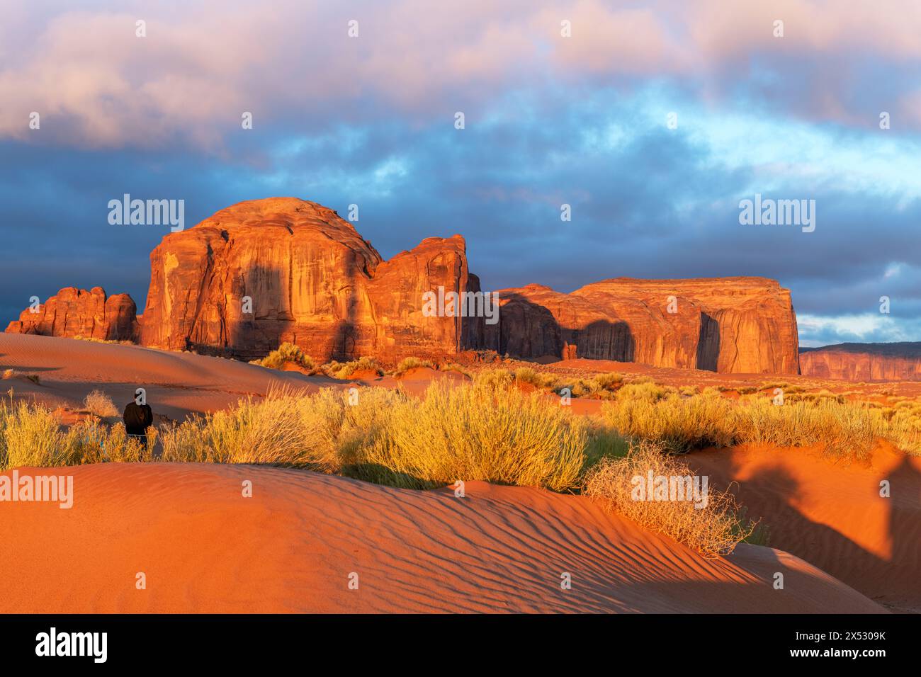 Die von der aufgehenden Sonne beleuchtete Berglandschaft wirft eine orange Farbe auf die Landschaft im Monument Valley, Arizona, ein Reiseziel für Abenteuer im Südwesten Stockfoto