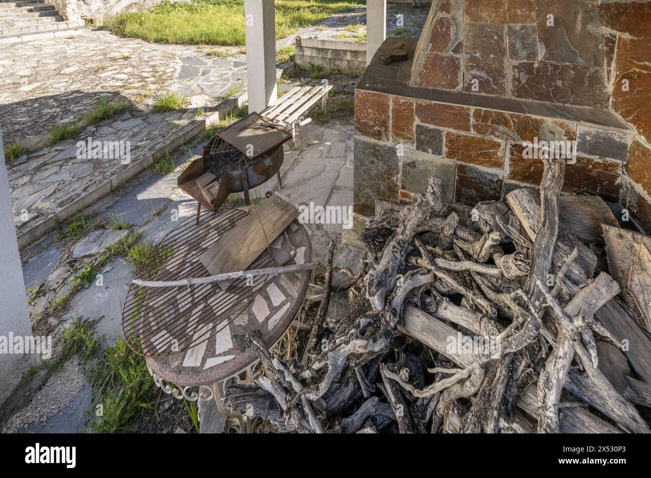 Ein Haufen trockenes Brennholz neben einem Grill Stockfoto