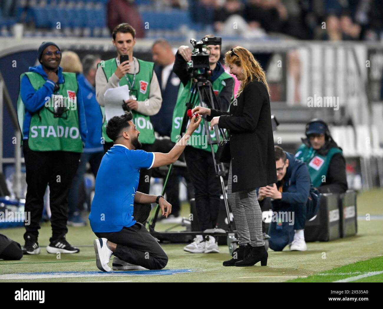 Heiratsantrag im Stadion vor Fernsehkameras kniet Hoffenheim-Fan vor der Freundin und bittet sie, ihn zu heiraten, übergibt Ringe Stockfoto