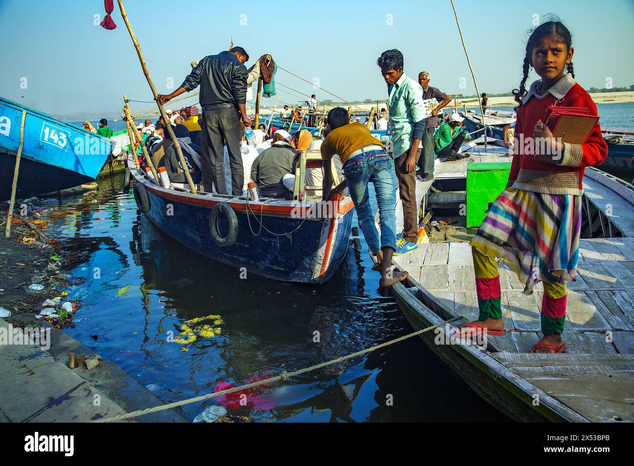Ein Boot voller Pilger, das vom Ufer in den Ganges bei Varanasi, Indien, geschoben wurde. Stockfoto