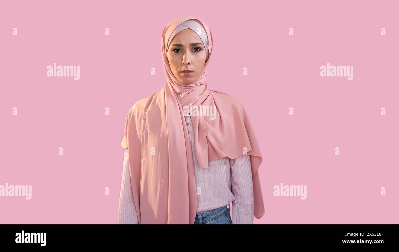 Verängstigte Frau. Angst Angst. Rechte der Frau. Gestörtes überwältigtes Mädchengesicht in Hijab muslimischem Kopftuch isoliert auf rosa Leerraum Hintergrund. Stockfoto