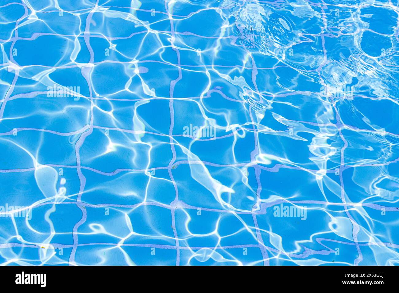 Blaue Schwimmbadwasseroberfläche und Hintergrund der Wellen. Sommer-abstrakte Reflexionskaustik im Schwimmbad. Stockfoto