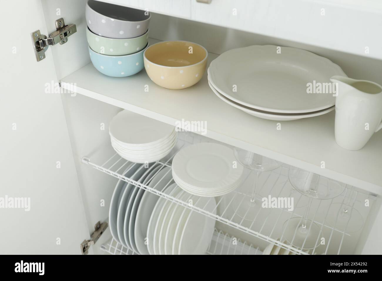 Reinigen Sie Teller, Schüsseln und Gläser auf den Regalen im Schrank im Innenbereich Stockfoto