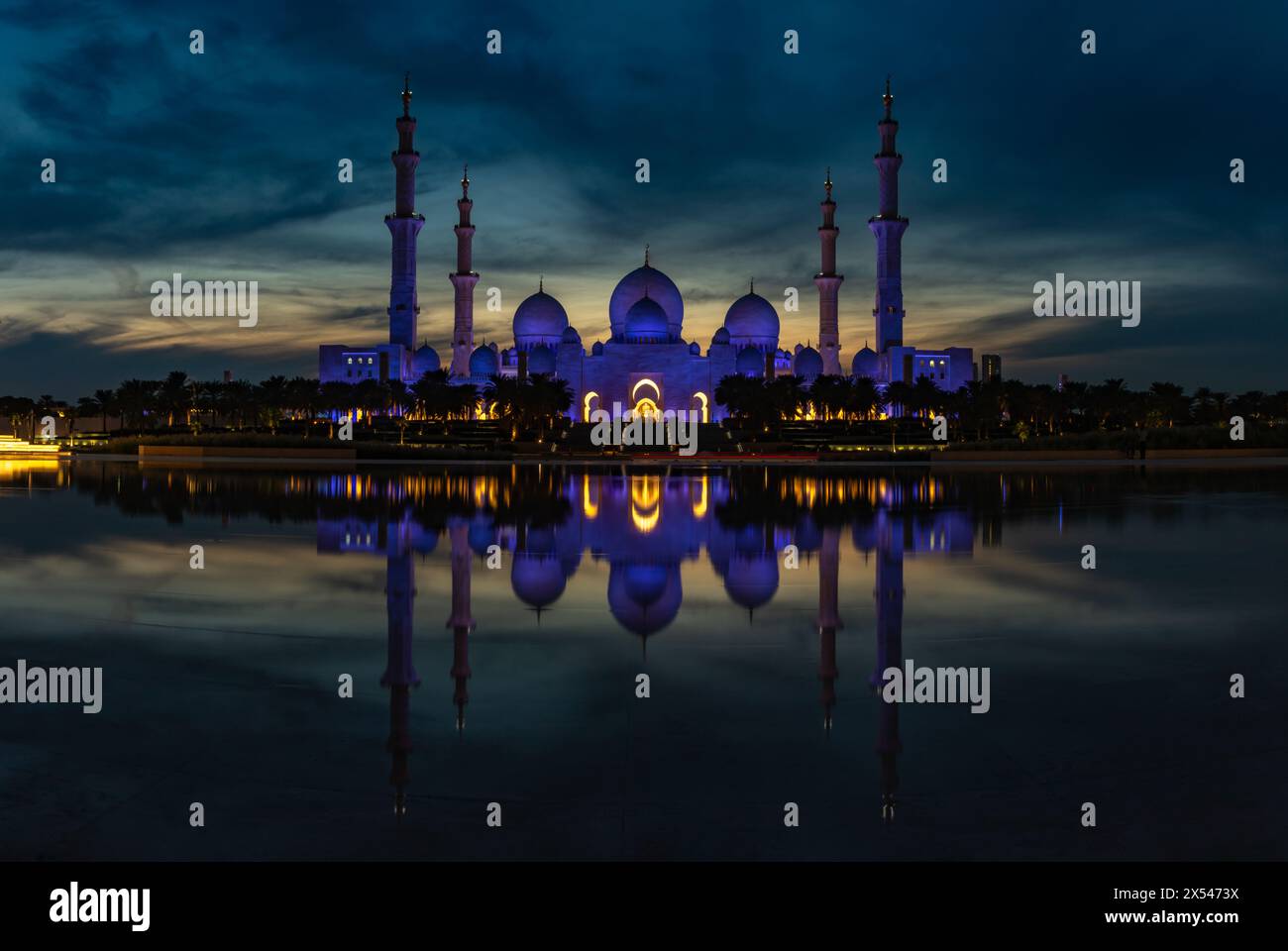 Ein Bild der beleuchteten Scheich-Zayed-Moschee, die sich nachts auf dem Pool der Oase der würde spiegelt. Stockfoto